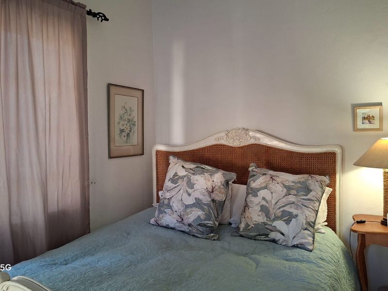 A cozy bedroom featuring neutral wall finishes and natural light through the window.