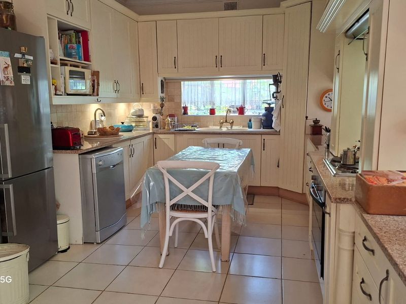 A functional kitchen featuring cream-colored cabinetry, granite countertops, tiled flooring, and integrated appliances, offering a classic layout with ample storage space.
