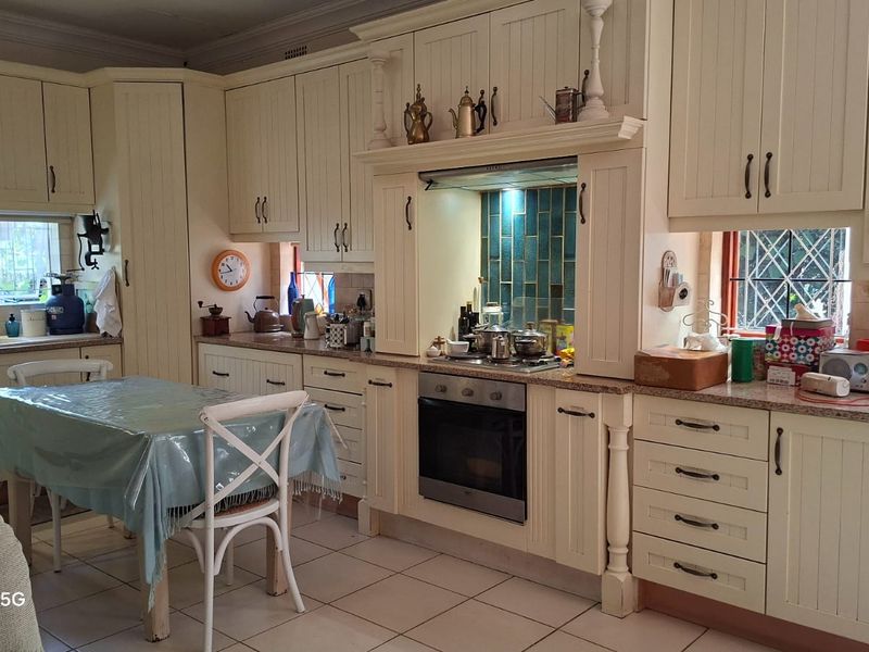 A traditional kitchen featuring cream-colored cabinetry, granite countertops, a built-in oven with extractor fan, and a tiled backsplash.