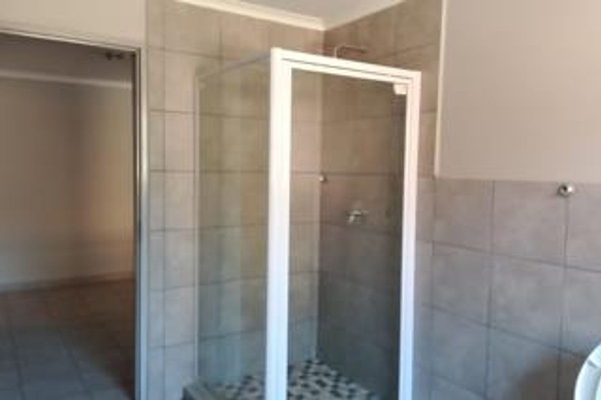 A functional bathroom featuring a glass-enclosed shower with neutral wall tiling and a clean, minimalist layout.