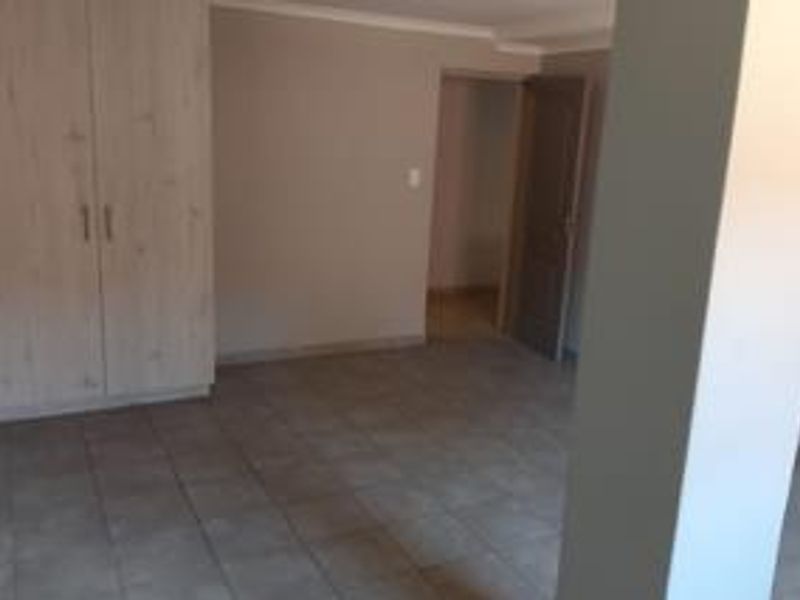 An empty bedroom featuring neutral tiled flooring and built-in cupboards, offering a clean and versatile space ready for personalization.