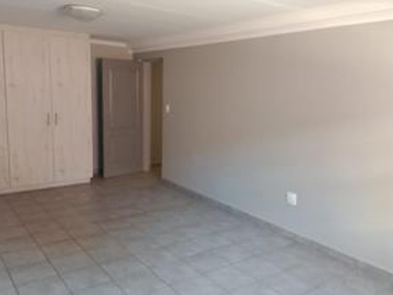 A spacious, empty bedroom featuring neutral tiled flooring, built-in cupboards, and a clean, minimalist aesthetic ready for personalization.