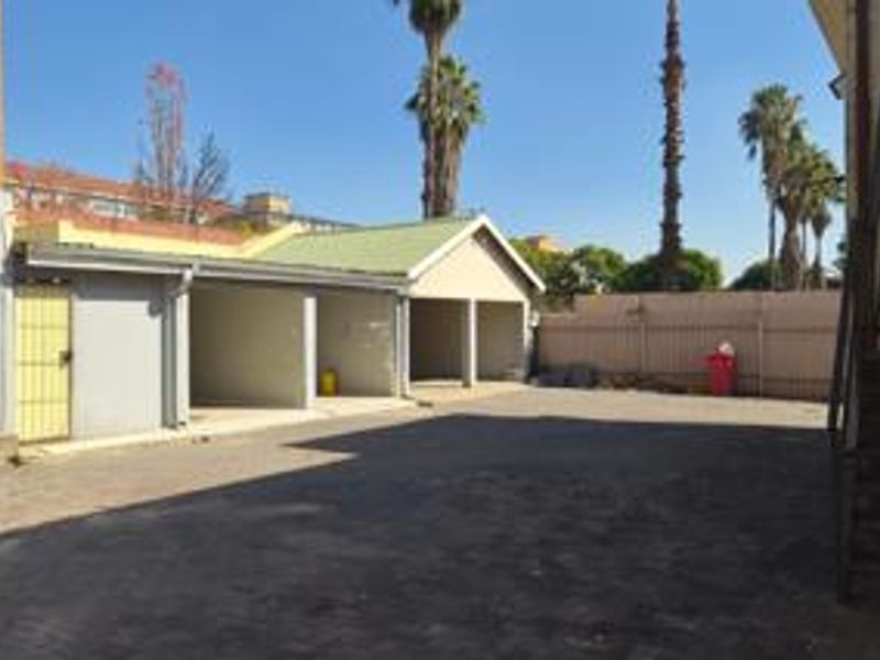 An open-bay garage area with paved driveway space and external metal staircase access.