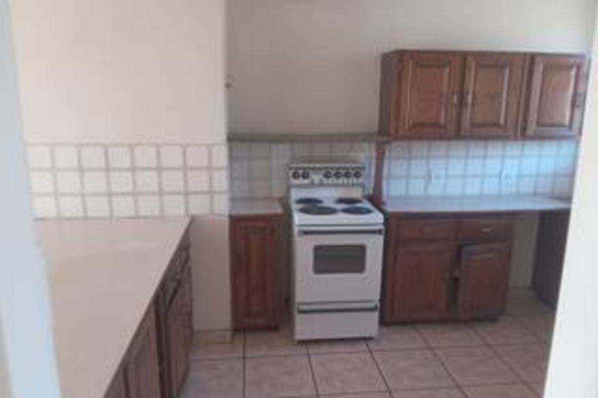 A dated kitchen featuring wooden cabinetry, tiled backsplash, and tiled flooring, providing a functional space ready for modernization.