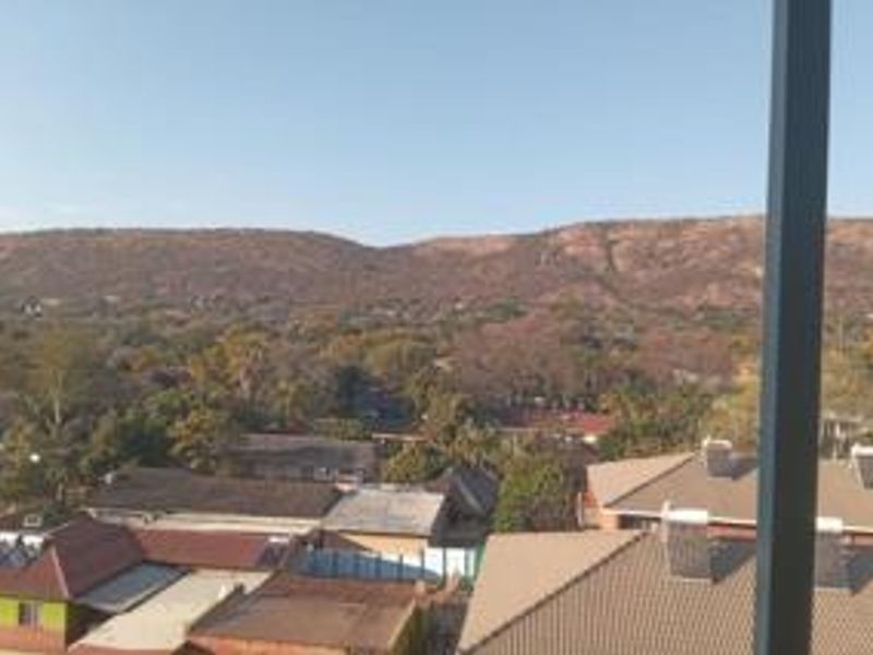 Elevated scenic view overlooking the surrounding neighborhood and distant mountain range, captured from an apartment balcony.