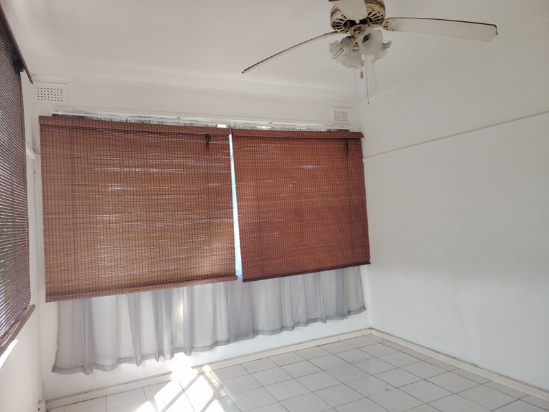 An empty bedroom featuring tiled flooring, a ceiling fan, and window blinds.