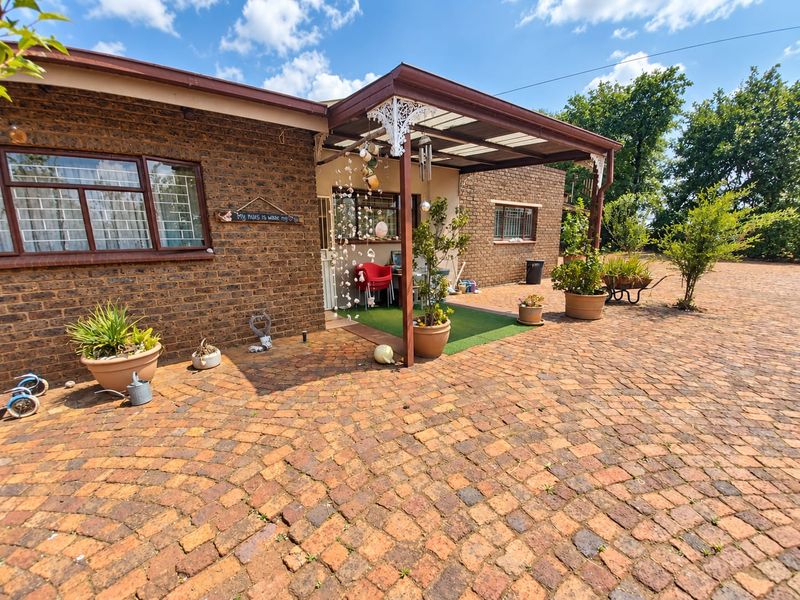 A covered patio area featuring brick construction, decorative ironwork, and a paved outdoor space, providing a functional transition between the home and garden.
