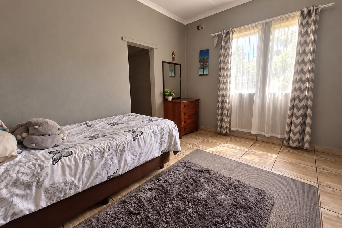 A well-lit bedroom featuring tiled flooring, coved ceilings, and security bars on the windows, offering a functional and comfortable living space.