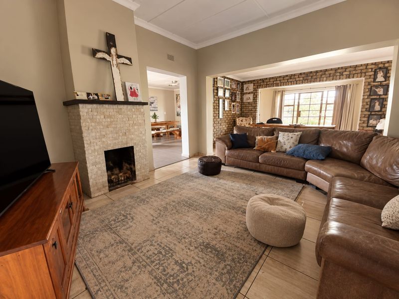 Spacious living room featuring a stone-clad fireplace, exposed brick feature wall, and neutral tiled flooring, creating a warm and inviting atmosphere.