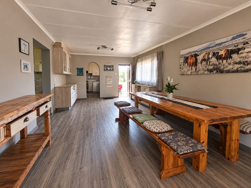 Spacious open-plan living and dining area featuring modern laminate flooring, neutral wall tones, and seamless flow into the adjacent kitchen and scullery.