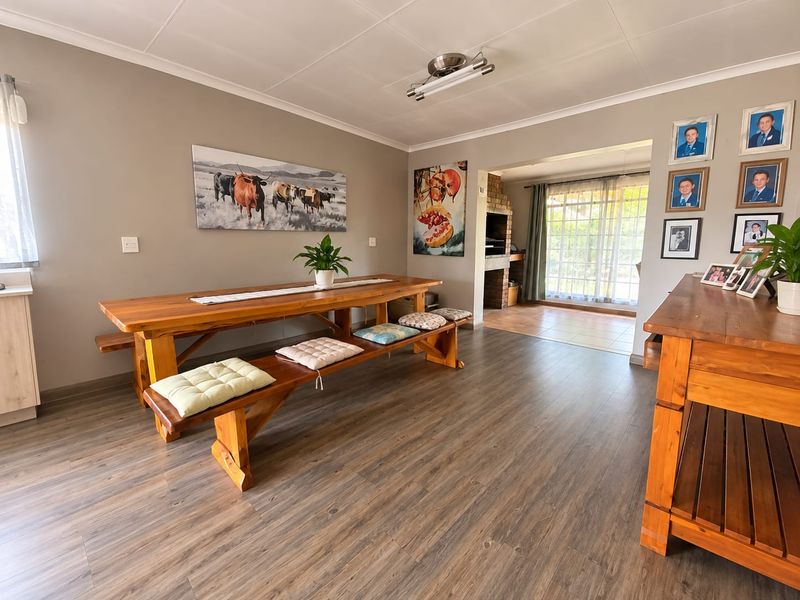Spacious dining area featuring durable laminate flooring and a built-in brick fireplace, with direct access to an adjoining patio through sliding glass doors.
