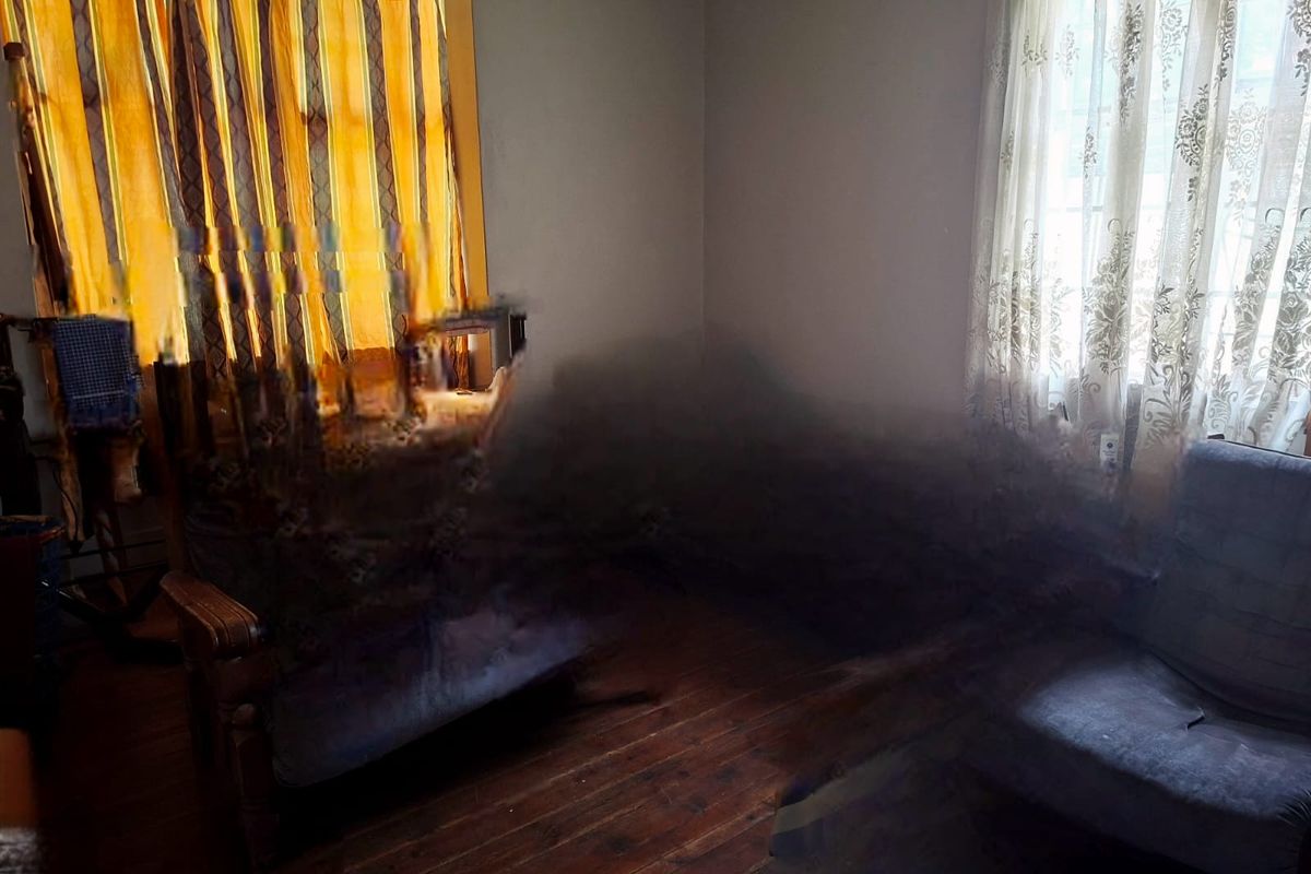 A living room area featuring hardwood flooring and coved ceilings, currently affected by significant image distortion and digital artifacts.