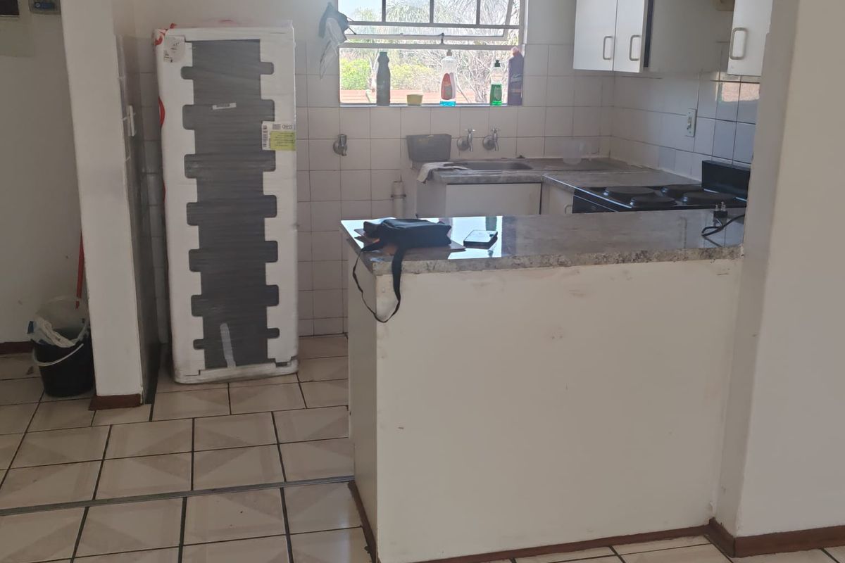 A functional kitchen featuring tiled flooring, granite countertops, and built-in cabinetry, offering a practical layout ready for modernization.