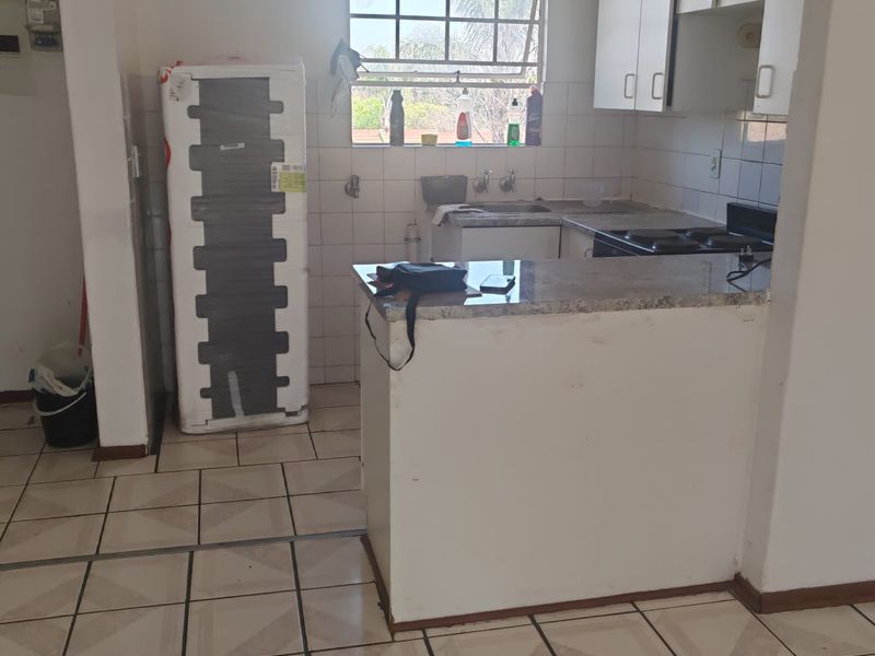 A functional kitchen featuring tiled flooring, granite countertops, and built-in cabinetry, offering a practical layout ready for modernization.