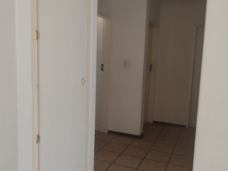 A functional hallway featuring neutral tiled flooring and access to multiple rooms, providing a clean and simple transition space within the townhouse.