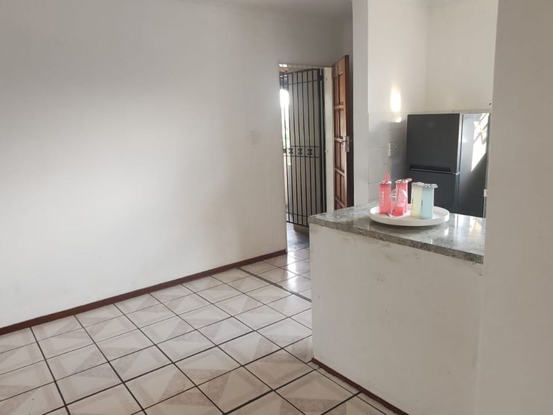 Open plan living area featuring tiled flooring and a granite breakfast counter, leading to an exterior security gate.