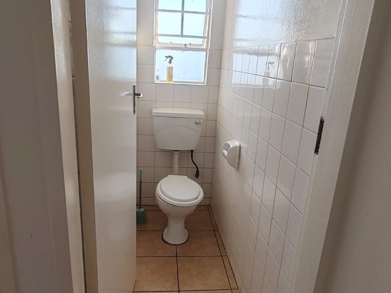 A functional bathroom featuring a bathtub and a separate toilet area with tiled walls and floors, offering a clean and practical layout.