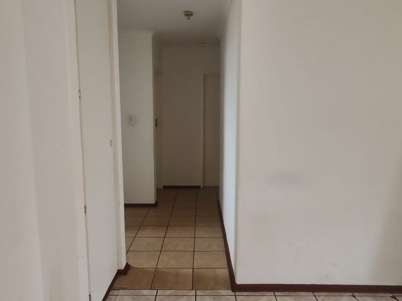 A neutral hallway featuring tiled flooring and access to multiple internal rooms, providing a clean and functional transition space within the townhouse.