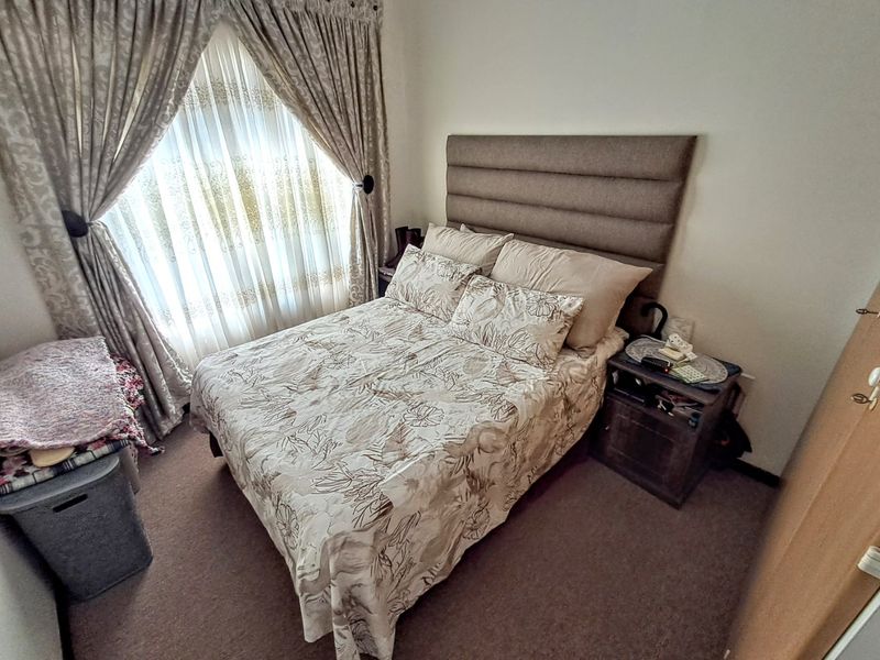 A compact bedroom featuring carpeted flooring and window treatments, providing a functional space for rest.