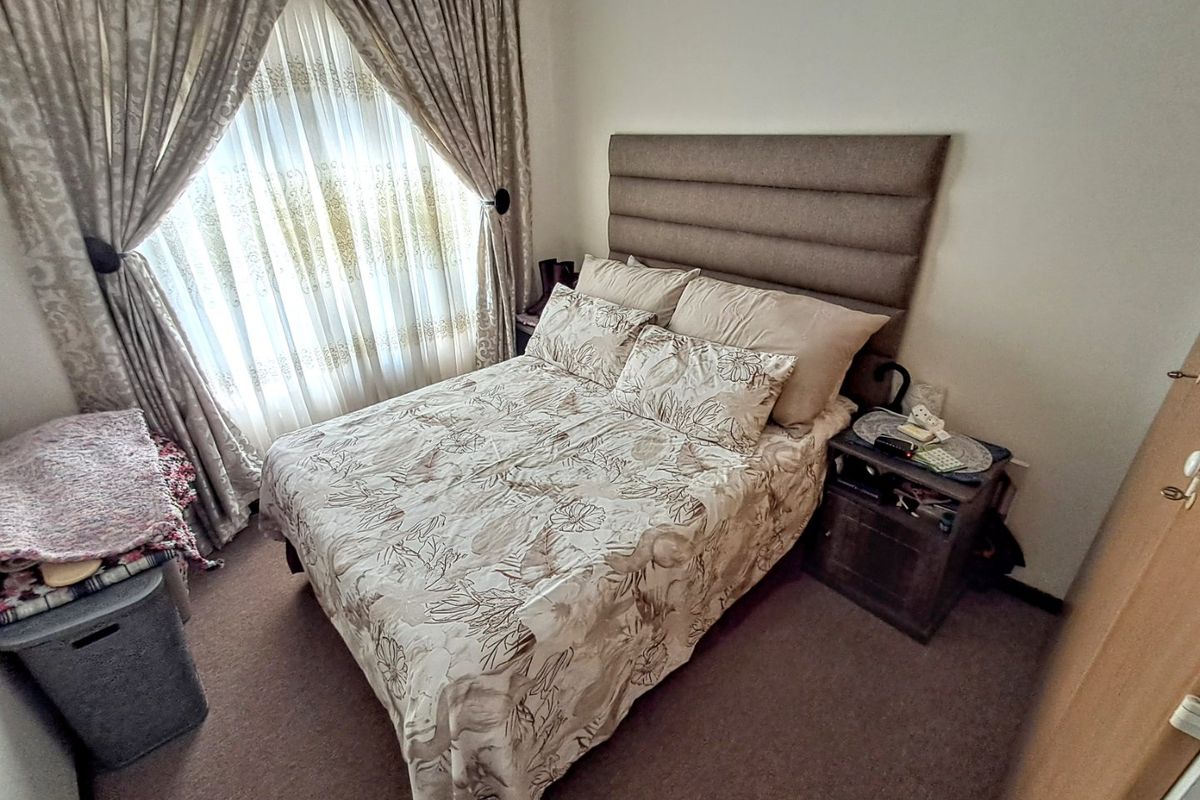 A compact bedroom featuring carpeted flooring and window treatments, providing a functional space for rest.