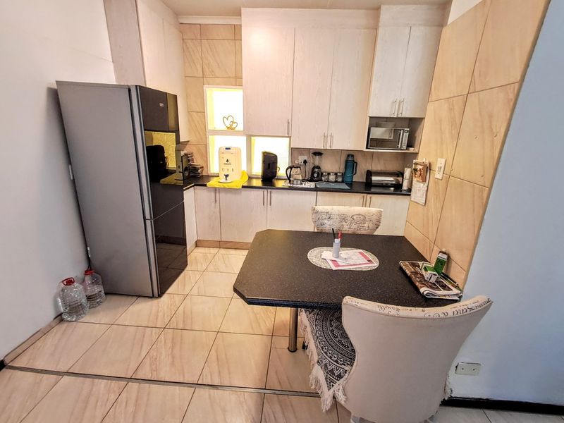A functional kitchen featuring light-toned cabinetry, dark countertops, tiled backsplash, and tiled flooring, providing a practical workspace for daily meal preparation.