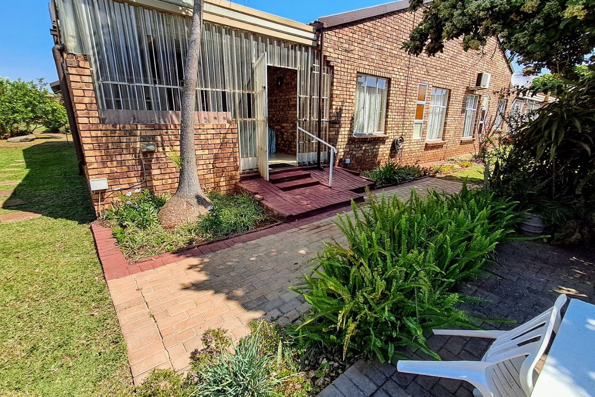 Rear view of the townhouse featuring a face brick facade, an enclosed patio area, and a paved garden walkway.