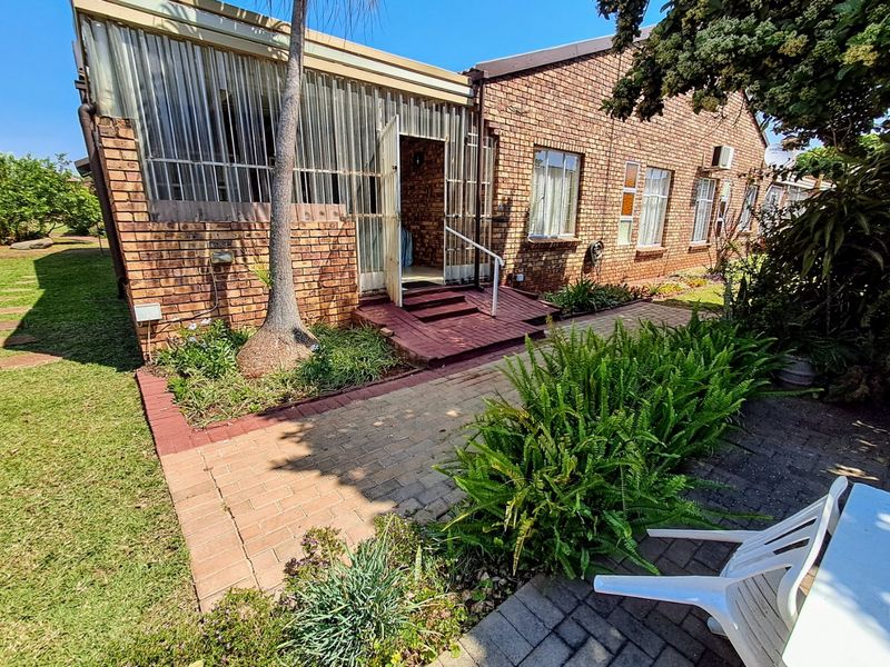 Rear view of the townhouse featuring a face brick facade, an enclosed patio area, and a paved garden walkway.