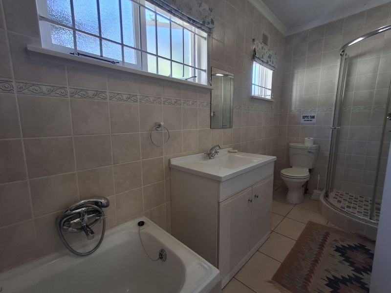 A functional bathroom featuring a bathtub, vanity cabinet, toilet, and a separate shower enclosure with tiled finishes throughout.