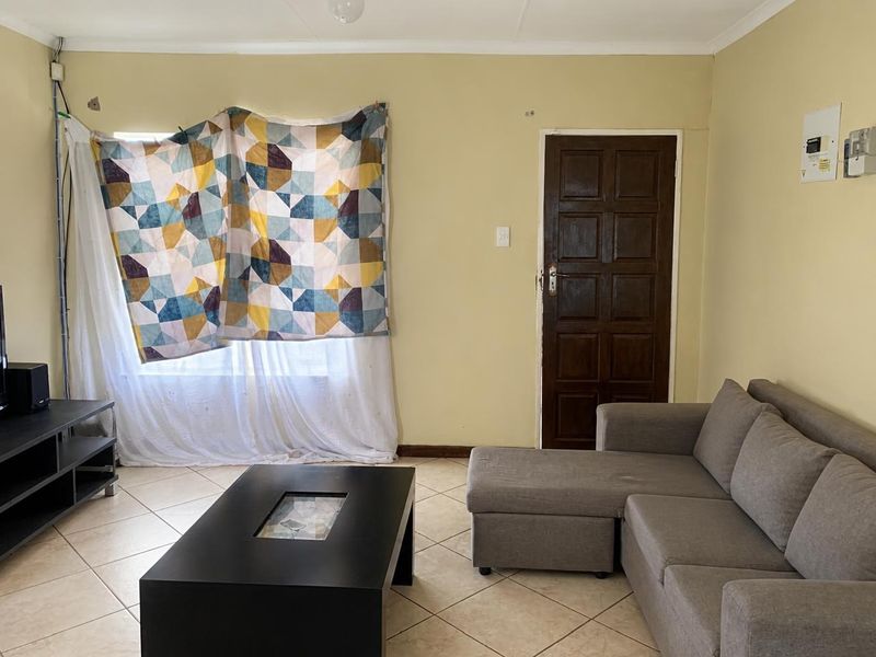 A living room featuring tiled flooring and a wooden panel door, requiring cosmetic updates to improve the overall aesthetic and finish.