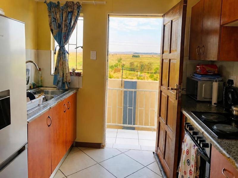 Compact kitchen featuring wooden cabinetry, electric hob, and direct access to a balcony with scenic rural views.