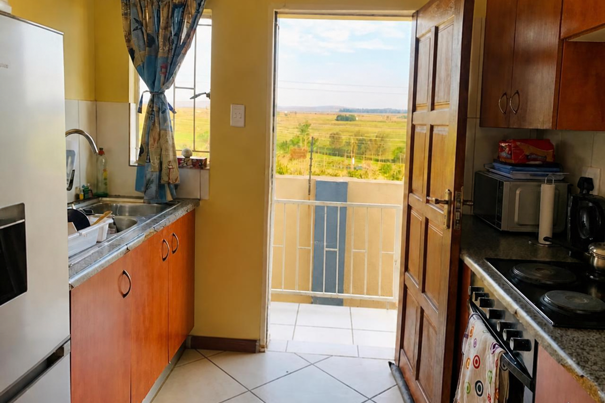 Compact kitchen featuring wooden cabinetry, electric hob, and direct access to a balcony with scenic rural views.