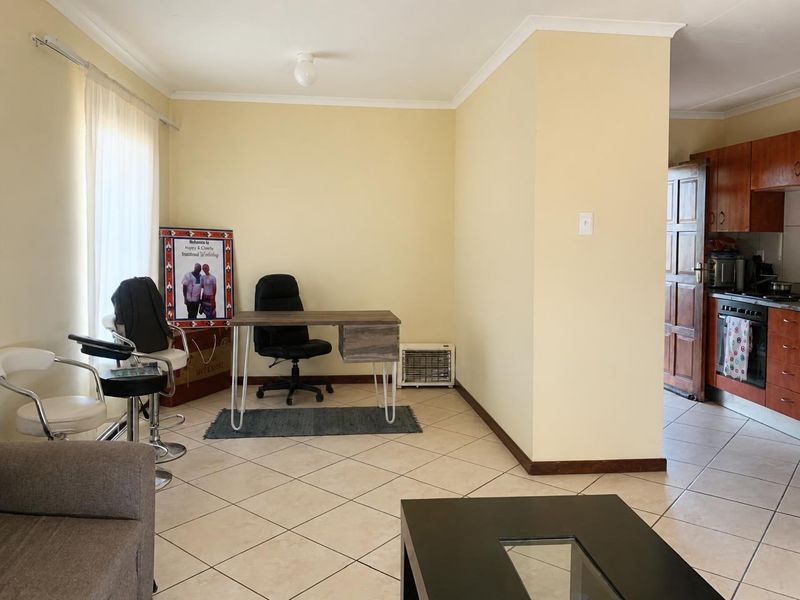 Open plan living area featuring tiled flooring and a connected kitchen with built-in cabinetry and appliances.