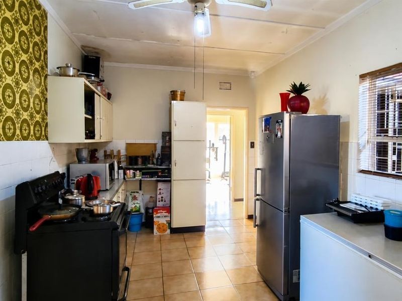 A functional kitchen featuring tiled flooring, built-in cabinetry, and a tiled splashback, requiring cosmetic updates to improve its overall aesthetic and condition.
