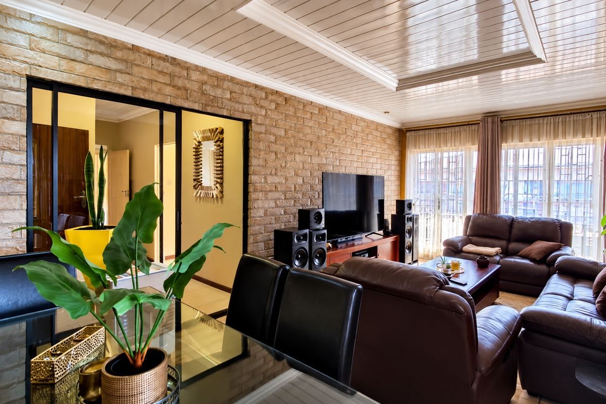 Spacious living room featuring an exposed brick feature wall, high-gloss tongue and groove ceiling, and large windows with security bars.