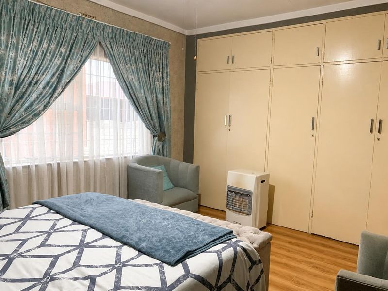 A bedroom featuring laminate flooring and extensive built-in cupboards, offering ample storage space and a neutral foundation for interior updates.