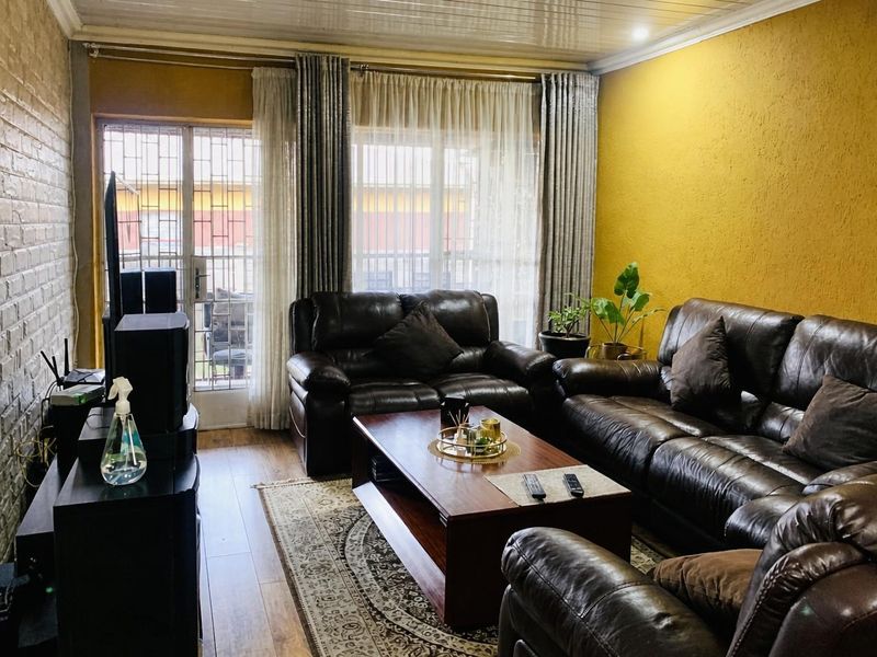 A comfortable living room featuring laminate flooring, a textured accent wall, and a sliding glass door with security gate providing natural light.