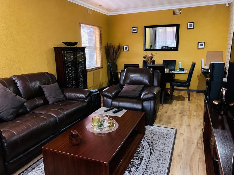 Open-plan living and dining area featuring laminate flooring, recessed lighting, and yellow-painted walls.