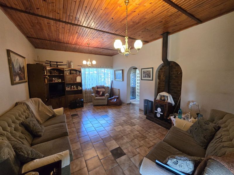 Spacious living room featuring a timber-clad ceiling, tiled flooring, and a traditional built-in brick fireplace with an arched alcove.