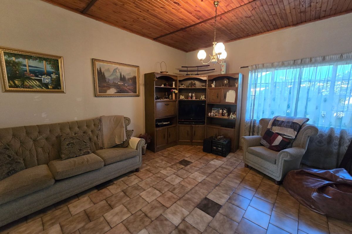 A living room featuring a timber tongue and groove ceiling, ceramic tiled flooring, and built-in corner cabinetry.