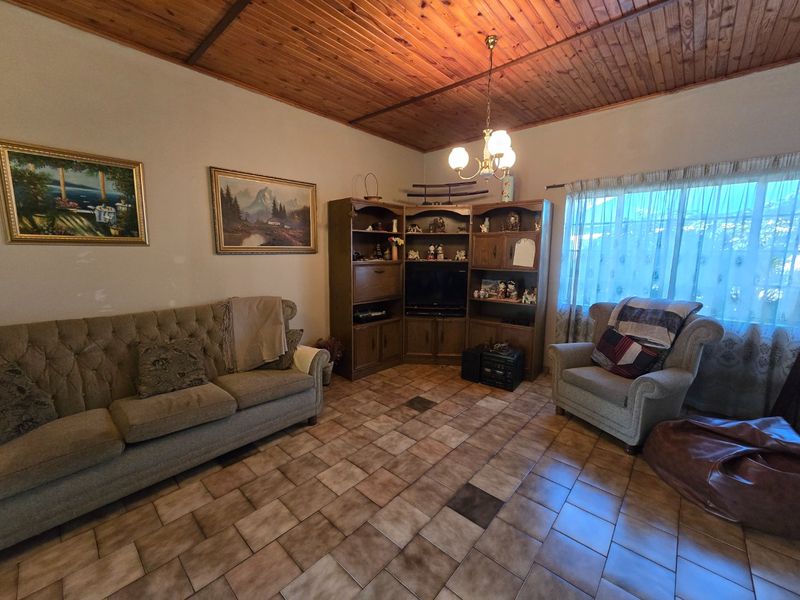 A living room featuring a timber tongue and groove ceiling, ceramic tiled flooring, and built-in corner cabinetry.