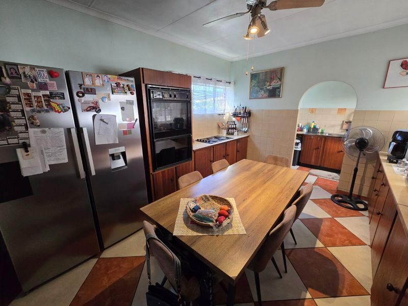 Open plan kitchen and dining area featuring built-in oven, cooktop, tiled flooring, and an archway leading to a secondary prep space.