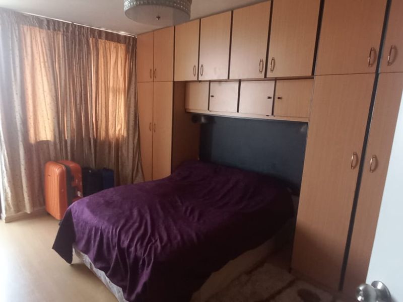 A bedroom featuring extensive built-in wooden cupboards and laminate flooring, with direct access to an outdoor area through a sliding door.