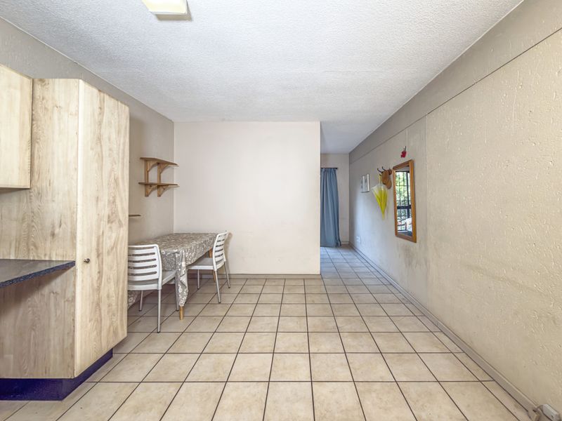Open plan living area featuring tiled flooring and built-in cabinetry, offering a functional space with potential for modern updates.