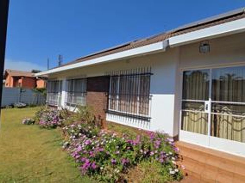 Rear exterior view of the house featuring a tiled patio, sliding glass doors, security bars on windows, and a well-maintained garden area.