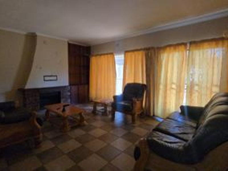 A living room featuring a brick fireplace, built-in shelving, and tiled flooring, with access to the outdoors through sliding glass doors.