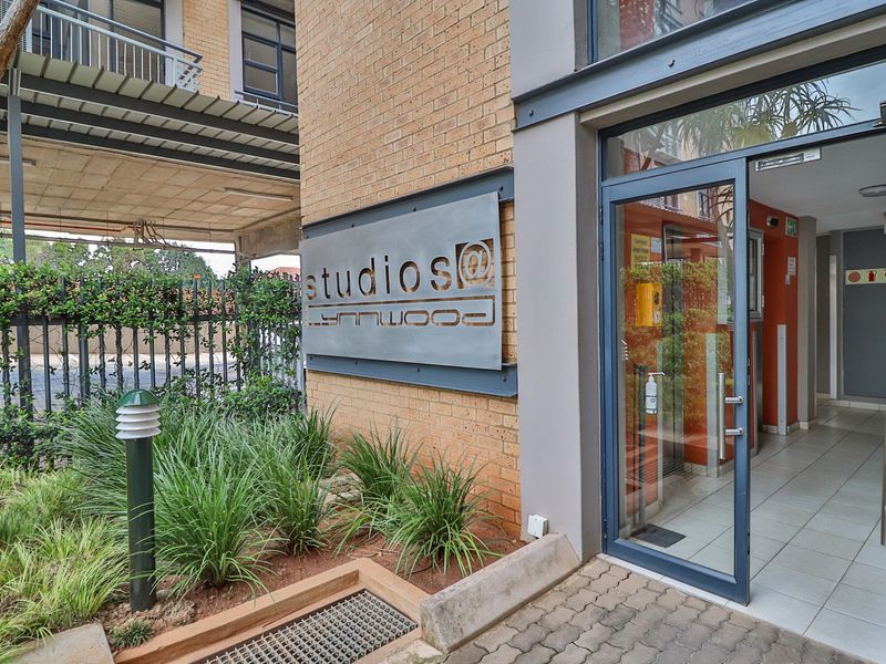 The main entrance to Studios at Lynnwood, featuring a brick facade, modern metal signage, and a glass door leading into the tiled lobby area.