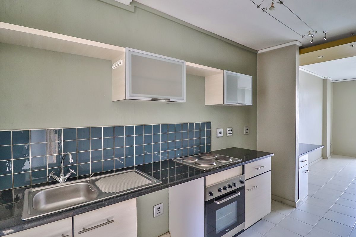 A clean, functional kitchen featuring built-in cabinetry, granite countertops, a stainless steel sink, and an integrated electric oven and hob.