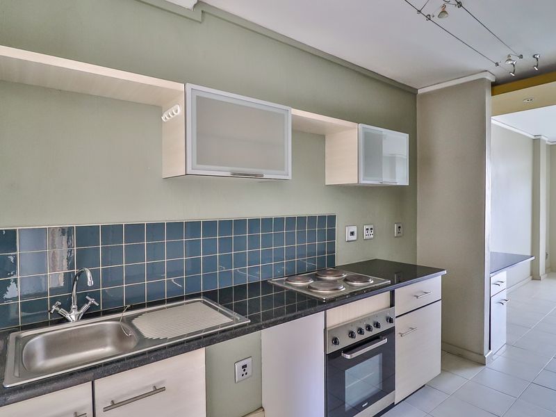 A clean, functional kitchen featuring built-in cabinetry, granite countertops, a stainless steel sink, and an integrated electric oven and hob.