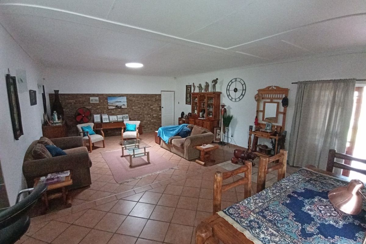 Spacious living area featuring tiled flooring, a coved ceiling, and an exposed brick feature wall, offering a comfortable and functional layout.