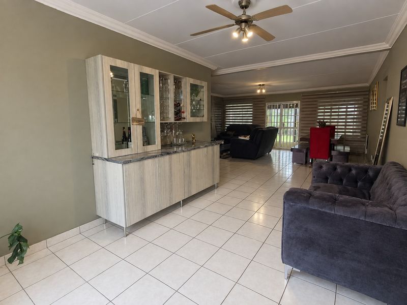 Spacious open-plan living area featuring tiled flooring, a ceiling fan, and built-in cabinetry, with direct access to the outdoor area through sliding glass doors.